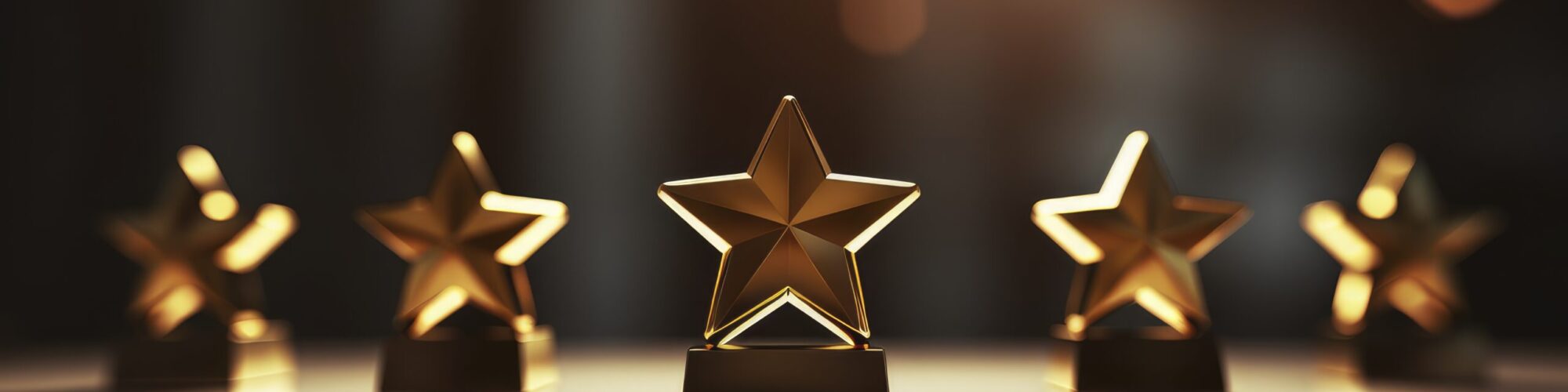 A close-up of golden star trophies arranged on a table, illuminated by soft lighting. A close-up of golden star trophies arranged on a table, illuminated by soft lighting.