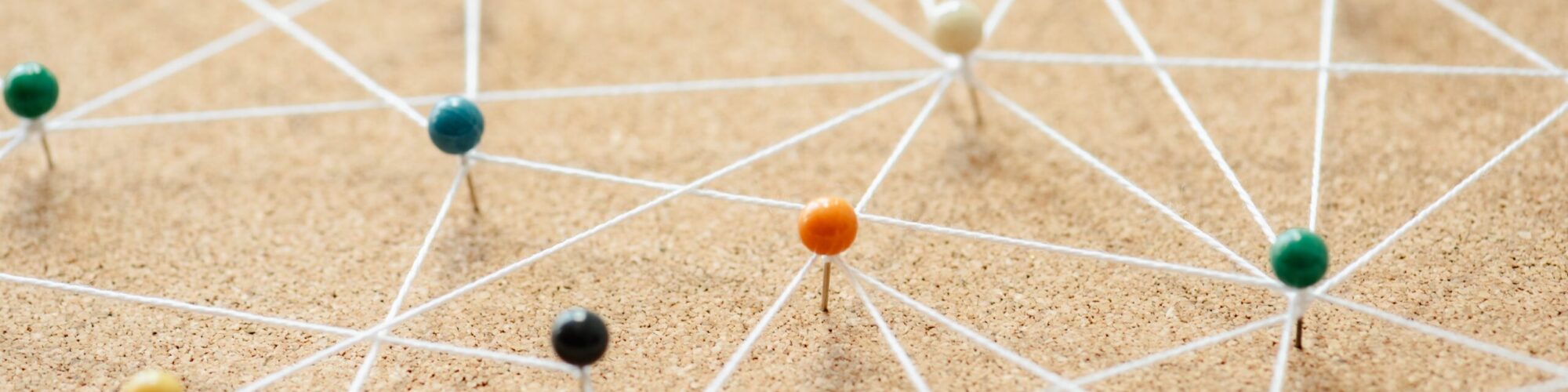 Colorful pins connected by string on a corkboard. Pins and strings form a network. Pins and strings illustrate connections. Pins and strings concept. Connection background, business network background
